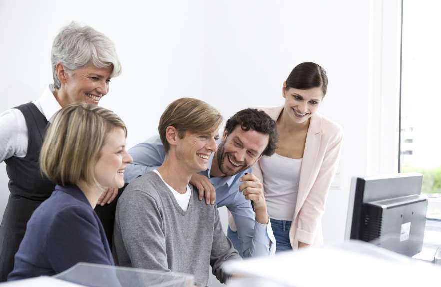 group of people similing and looking at a computer screen